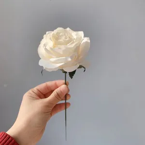 Close-up detail shot of a single white artificial silk rose flower with green stem.