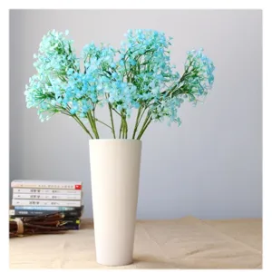 Fiori artificiali di gipsofila blu in vaso di ceramica bianca per arredamento e foto.