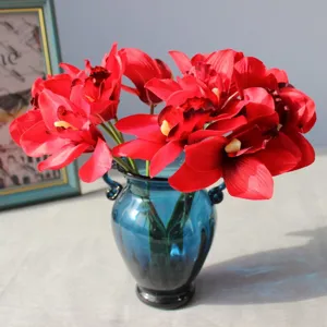 Detailed view of artificial red orchids in a blue glass vase, perfect for home decor.