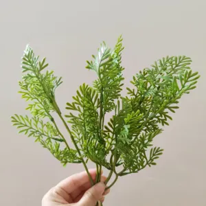 Close-up detail of artificial fern green leaves plant branch for home wedding decor display.