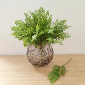 Artificial fern plant in geometric glass vase, modern home decor green leaf detail shot.