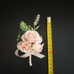 Gedetailleerd uitzicht op de lichtroze kunstmatige rozenboutonnière met bladeren en lint.