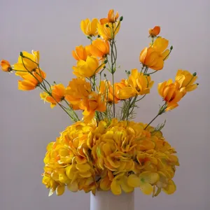 Gros plan d'un bouquet de fleurs artificielles jaunes en soie dans un vase blanc, détail déco.