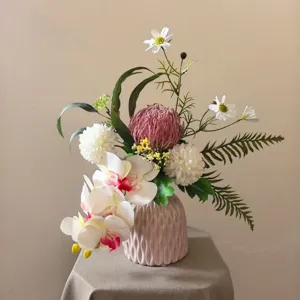 Détail de bouquet de fleurs artificielles exquis avec orchidées en vase céramique.