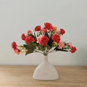 Detailaufnahme künstlicher Seidenblumen in einer weißen Keramikvase für die Inneneinrichtung.