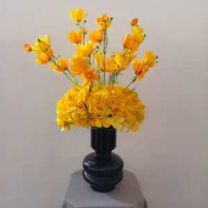 Bouquet de fleurs artificielles jaunes avec vase noir pour table de maison et restaurant.