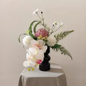 Bouquet de fleurs artificielles déco maison avec vase noir, arrangement floral élégant table.