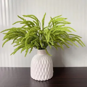 Detailed view of the artificial green plant in a white ceramic vase, perfect for home decor.