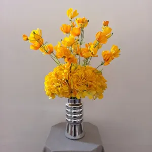 Bouquet de fleurs artificielles jaunes en vase argenté, détail déco de table élégant.