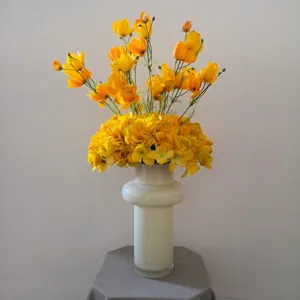 Bouquet de fleurs artificielles jaunes dans un vase en céramique blanche pour la décoration.