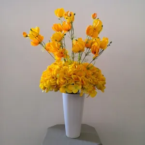 Bouquet de fleurs artificielles jaunes dans un vase blanc pour decoration interieure.