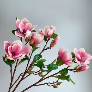 Nahaufnahme des künstlichen rosa Magnolienblütenzweigs mit realistischen Blüten und grünen Blättern.