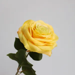 Primo piano dettagliato di una grande rosa gialla artificiale con petali di seta realistici.