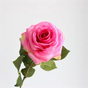 Dettaglio di fiore di rosa artificiale, testa di rosa rosa in seta con bellissime foglie verdi.
