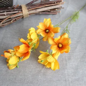 Gros plan sur le détail de fleurs artificielles en soie cosmos jaune à 6 têtes pour décor.