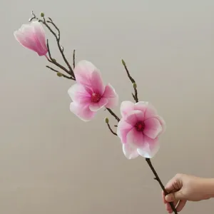 Primo piano del ramo di magnolia artificiale con fiori rosa in seta e steli decorativi.
