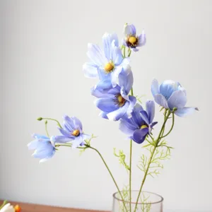 Gros plan de fleurs de cosmos artificielles bleues en vase, détail floral élégant déco.