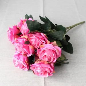 Primo piano dettagliato di un mazzo di rose artificiali rosa con foglie su tessuto.