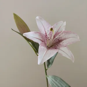 Artificial lily flower detail close-up showing realistic pink spotted petals and green stem.