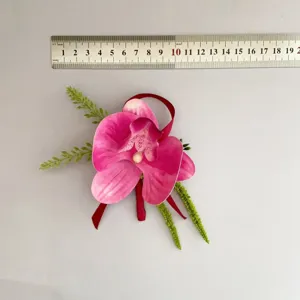 Vista ravvicinata dettagliata del fiore artificiale per occhiello orchidea rosa con nastro.