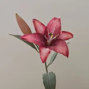 Detailed close-up of artificial retro lily flower stem, elegant red petals and green leaves.