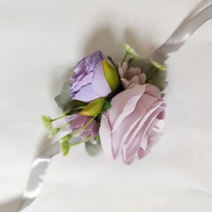 Primo piano dettaglio fiore da polso in rosa viola artificiale con nastro argento elegante.
