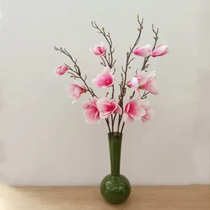 Fiori di magnolia artificiali in vaso di vetro verde, scatto di dettaglio decorazione.