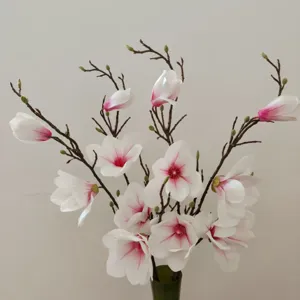 Vista dettagliata di rami di magnolia artificiali con petali bianco-rosa realistici e stelo marrone.