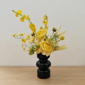Vue détaillée d'un bouquet de fleurs artificielles jaunes dans un vase noir moderne pour table.