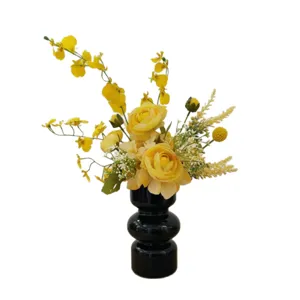 Composition florale artificielle jaune en vase noir pour décoration de table maison.