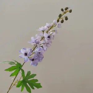 Detail view of a single stem artificial delphinium flower featuring purple petals and green leaves.
