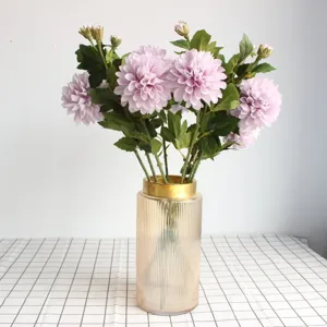 Détail exquis d'un bouquet de fleurs de dahlias artificiels violets dans un vase en verre.