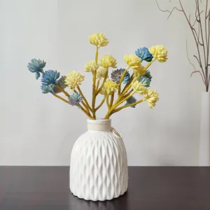Vista dettagliata di composizione floreale di succulente artificiali in vaso di ceramica bianca.