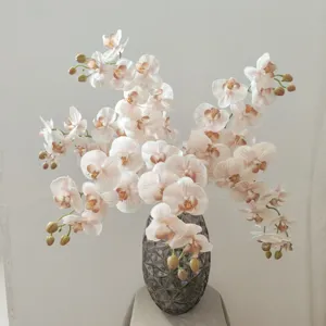 Dettaglio di orchidee phalaenopsis artificiali 3D in vaso decorativo scuro per interni.