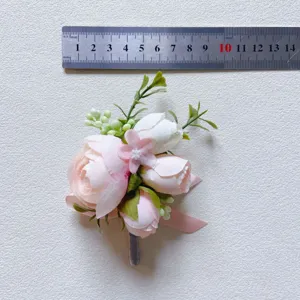 Detail shot of artificial pink and white flower boutonniere with size reference ruler.