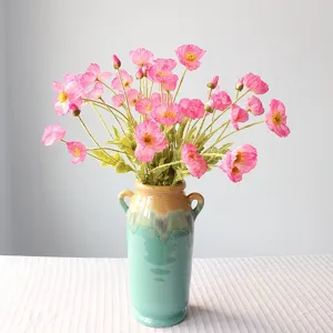 Detail view of coral pink artificial poppy silk flowers in a ceramic vase for home decor.