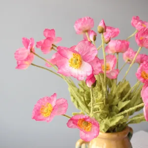 Close up detail of coral pink artificial poppy flowers bouquet with flocked texture and ceramic vase.