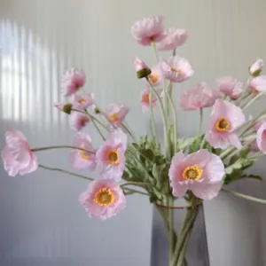 Close-up detail view of coral pink artificial Iceland poppy flowers in a sleek glass vase.