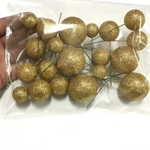 Bolas de pastel con purpurina dorada y tallos de alambre para decoración festiva.