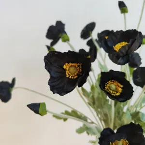 Close up view of black artificial Iceland poppy flowers with detailed yellow centers and stems.