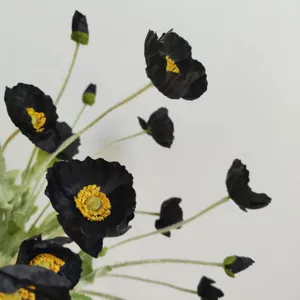 Close-up detail of artificial black poppy flower with yellow center and realistic flocked stem.