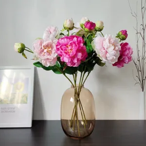 Artificial pink peony and silk flower bouquet in glass vase for home decoration