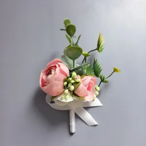 Detalle de botonera de boda rosa, con rosas artificiales y hojas verdes para el novio de la boda.