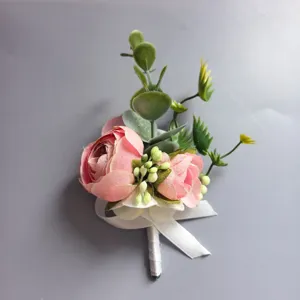 Primer plano detalle de ojal de flor artificial rosa con hojas verdes y cinta blanca.