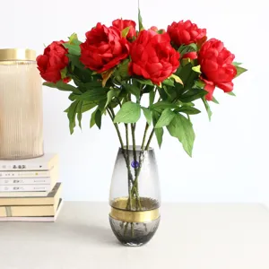 Detailed view of red artificial peony silk flower bouquet in glass vase for home decor