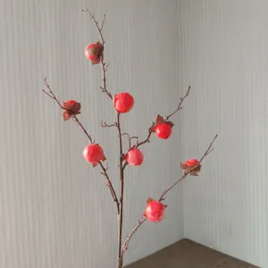 Branche de kaki artificielle en gros plan, mini tiges de plaqueminier pour déco et photo.