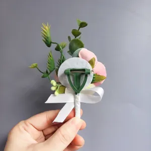 Detalle trasero de la boutonnière de flor artificial rosa con alfiler y cinta blanca.