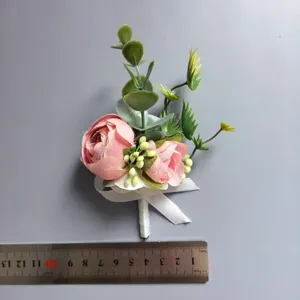 Vista detallada del ojal de flor artificial rosa con hojas verdes para bodas y ceremonias.