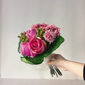 Artificial pink rose and hydrangea flower bouquet detail view with realistic green leaves.