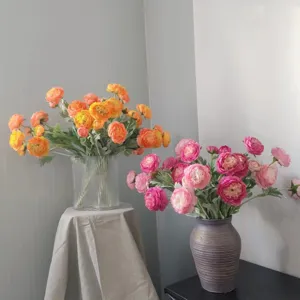 Dettaglio di bouquet di fiori artificiali in seta ranuncoli con vivaci tonalità arancio rosa.